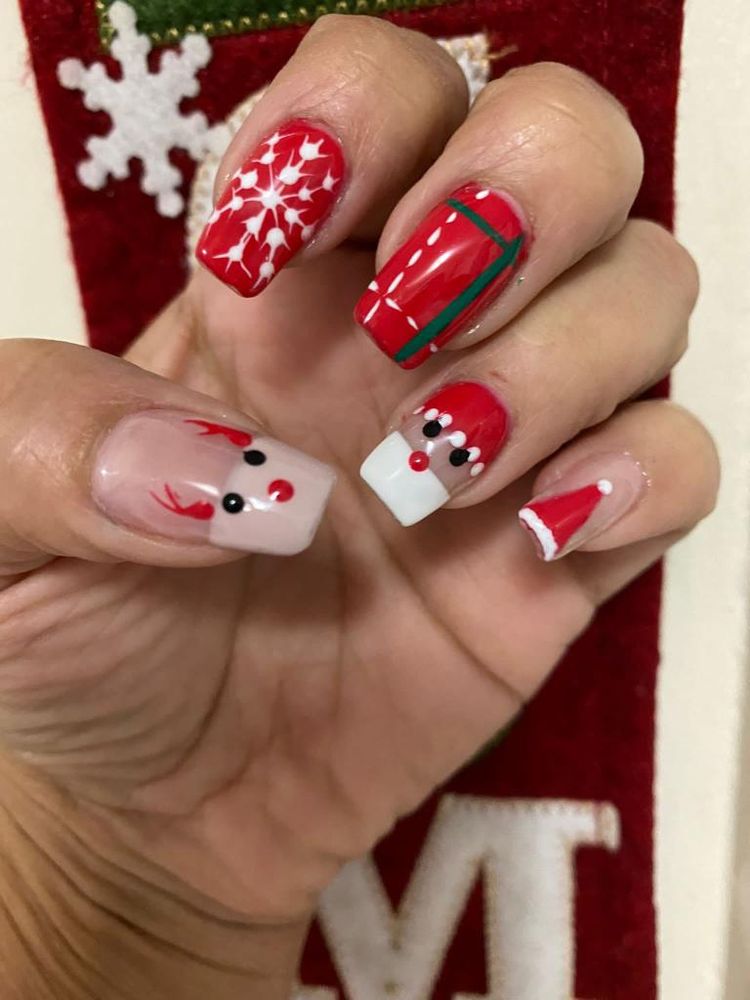Red holiday-themed nail art with snowflake and Santa designs at Tiptop Hair Designs